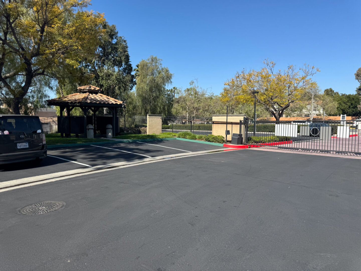 Image of a black color road with some trees and houses